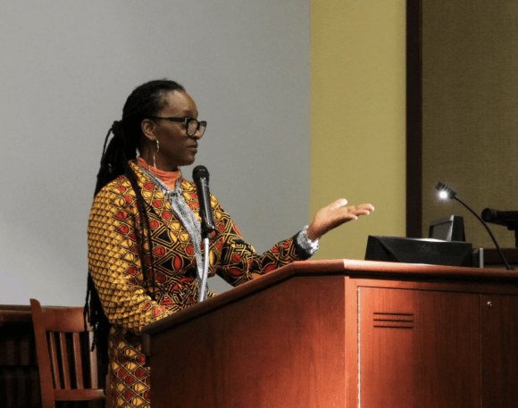 Woman (Chika Unigwe)standing at podium speaking to audience